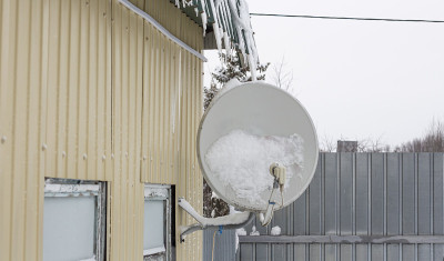 一场雪后，卫星天线被固定在一所房子的墙上