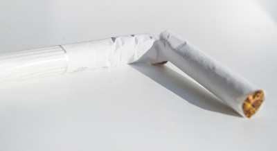 一个破碎的香烟在明亮的阳光下的白色背景上的特写
