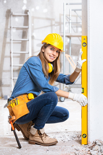 有吸引力的年轻女性建筑工人检查水平