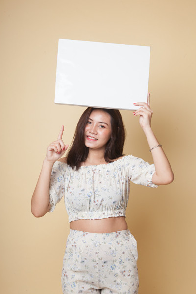 年轻的亚洲女人指着空白的标志。