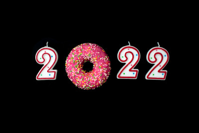 红白相间的2022号蜡烛和黑色背景的甜甜圈。从以上观点。圣诞节和新年的概念