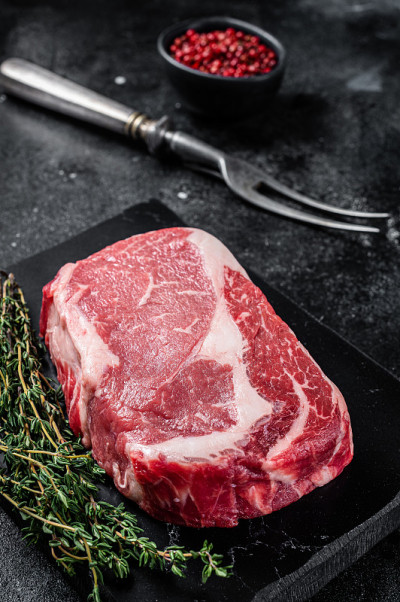 肋眼牛排，生肋眼牛排，百里香和粉盐拌牛肉。黑色背景。俯视图