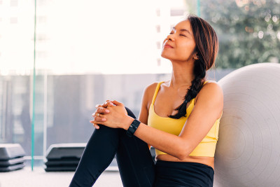 美丽的亚洲女人坐在旁边的普拉提瑞士球。女性健身模特在镜头前摆姿势