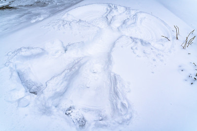 一个雪天使在冬天被雪覆盖的地面上创造的近距离视图