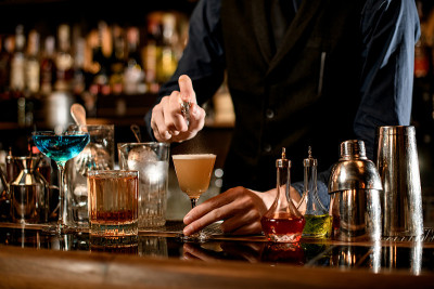 酒保轻轻地将酸味鸡尾酒洒在玻璃杯上。