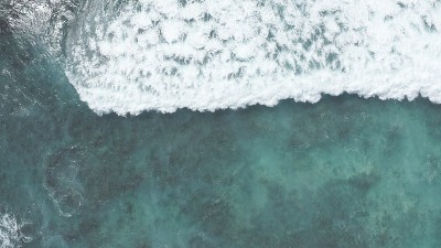在黄金时刻飞过海洋。巨大的波浪在海洋中激起泡沫和水花。夏威夷瓦胡岛上的太平洋海水的蓝绿色。