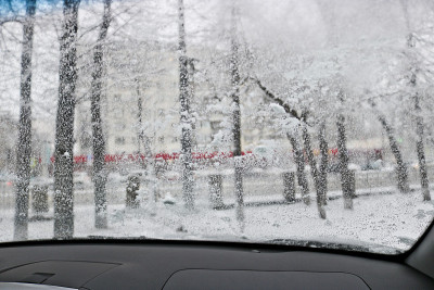 雨和湿雪期间从汽车挡风玻璃观看。在市内开车时能见度低。雪道路。