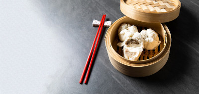 中国传统美食的概念。饺子点心在竹蒸笼内用文字抄写空间。亚洲食物背景