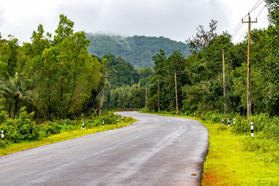 美丽的视角照片的道路曲折的柏油路通过郁郁葱葱的绿色森林地区，向热带山区。这张照片是在雨后拍摄的，当时