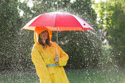 女人穿着雨衣带着雨伞在雨中