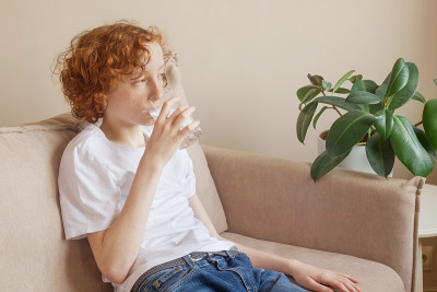 青少年在室内用玻璃杯喝水