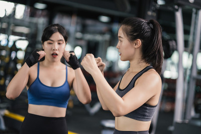 年轻的亚洲女子运动训练拳击手带手腕与教练，拳击练习运动搏击或与伙伴在健身馆锻炼健康的生活方式和自我防