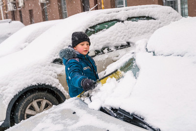 孩子帮助清理汽车上的雪