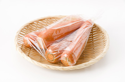 新鲜胡萝卜装于塑料袋，竹制滤锅，白色背景