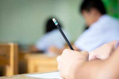 学生拿着铅笔在试卷上写下问题的答案