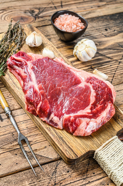 带骨的生肋眼牛排。大理石牛肉肋眼。木制背景。俯视图