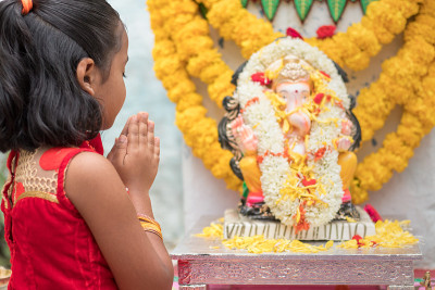 在家里举行象头象或vinayaka Chaturthi节日仪式时，女孩在主象头象神像前闭上眼睛和交叉