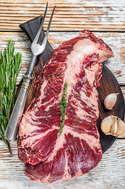将鲜嫩的牛肉挂在切菜板上。白色木制背景。俯视图