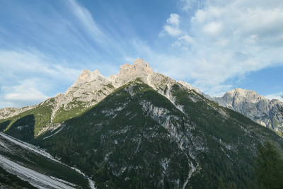 郁郁葱葱的山坡全景，中间有一些小灌木和石头。后面是意大利白云岩的高链。原始和荒凉的景观。孤独和冷静
