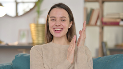 积极的年轻妇女在家鼓掌的肖像