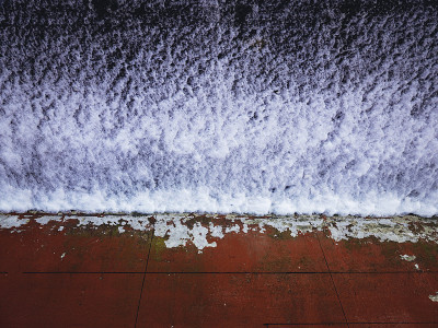风化红色混凝土砌块墙，油漆剥落，地面上有雪