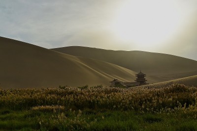典型的中国风格建筑和鸣沙山与黄花日落在敦煌，甘肃省，中国。