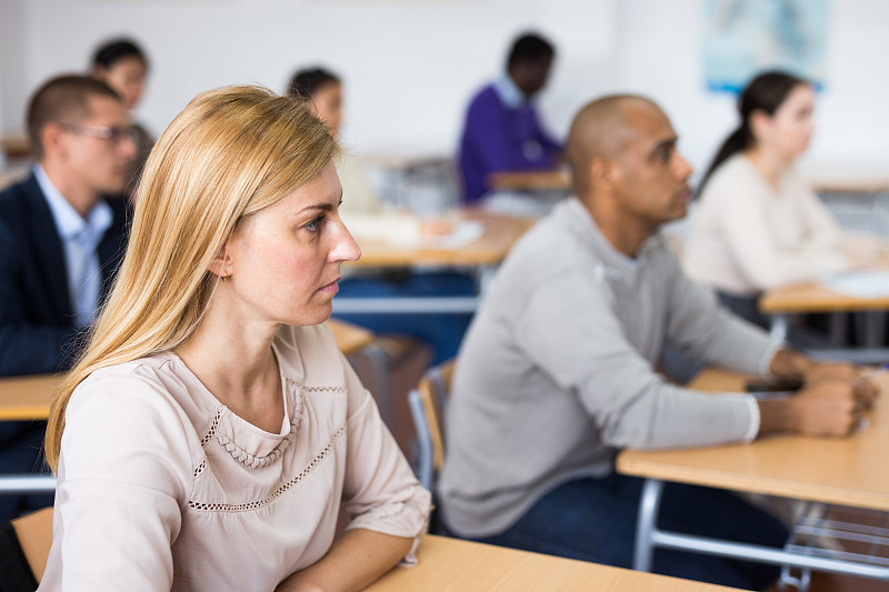 一位感兴趣的成年女子坐在学校礼堂里上课