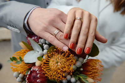 新婚夫妇的手与结婚戒指在婚礼花束的protea，复制空间。新婚夫妇，新娘和新郎，手拿戒指，特写