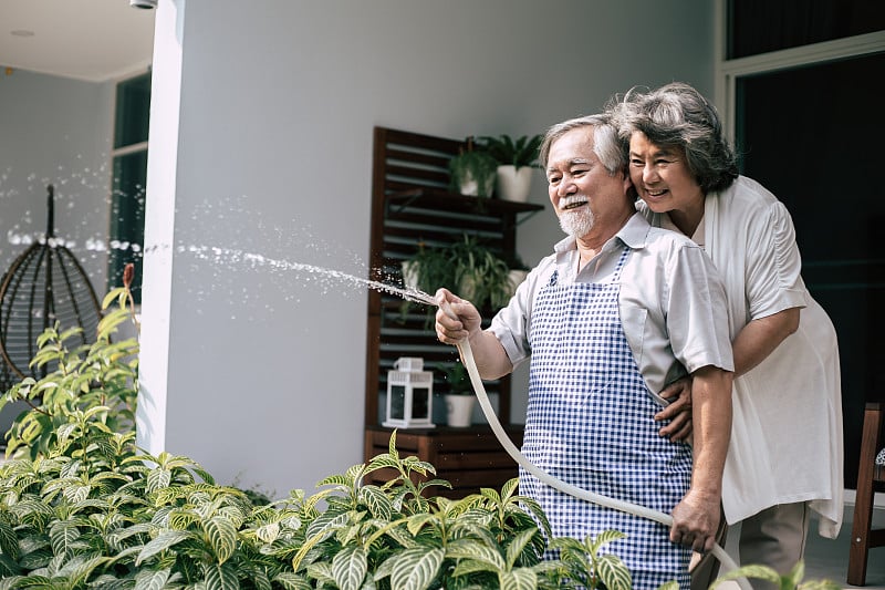 一对老夫妇在自家花园里浇花