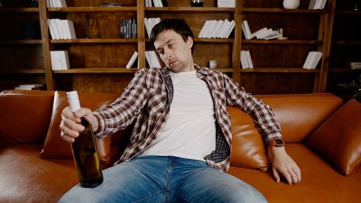 年轻男性酗酒者需要医疗和心理帮助。男人嗜酒成瘾，不能在圣诞节和新年前夜呆在家里的沙发上。一个醉汉在圣