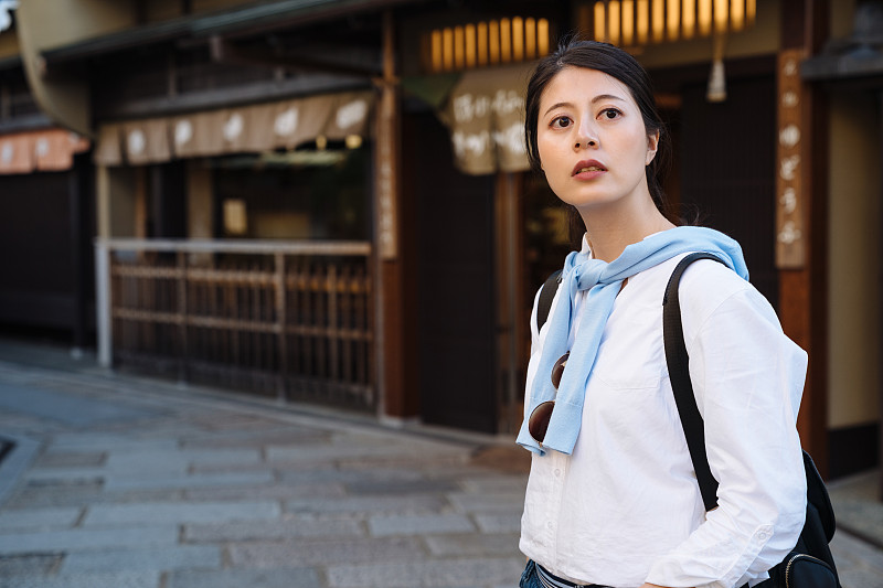 美丽的亚洲女旅行者的肖像站在历史悠久的日本京都九南扎卡街凝视着距离好奇