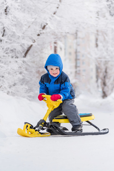 冬天，一个小孩坐在雪地摩托上