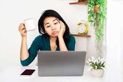 亚洲商业女性累了从努力工作手握咖啡杯感觉困倦坐在办公桌