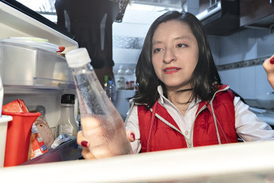 一个残疾的拉丁妇女在冰箱里找一瓶水