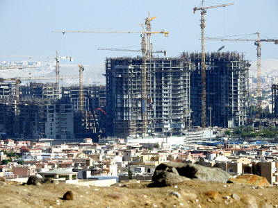 在埃及的新建筑工地上，占地数亩的豪华房地产住宅楼正在用起重机施工