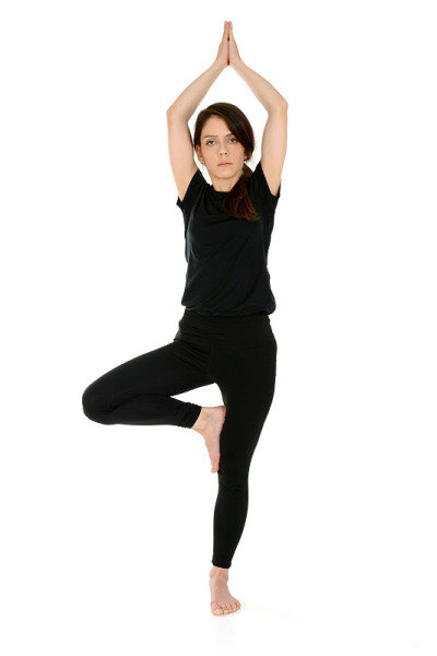 年轻女子做瑜伽体位树姿势Vrksasana