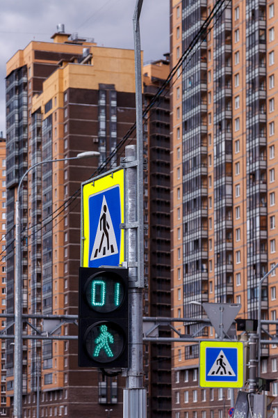 道路标志和人行横道标志。都市建筑背景中的交通信号灯与人行横道。一秒钟内行走的人