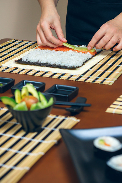厨师双手将食材放在米饭上