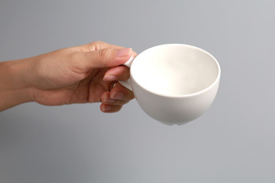 手里拿着一个白咖啡杯