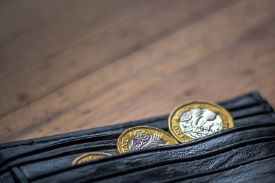 新英国英镑英镑硬币随意放置在黑色钱包上的木制表面。财富，金钱，现金，零钱。