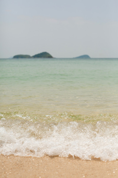 阳光照在水面上。砂质底。海浪和泡沫在海岸上