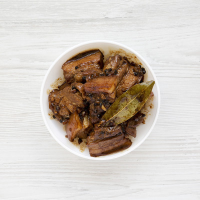 白色木桌上自制的菲律宾阿多波猪肉，俯视图。平躺着，从上面，头顶上。特写镜头。