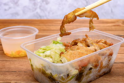 筷子从快餐盒中夹起一块油炸的鸡肉