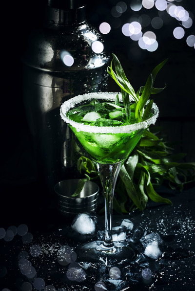 绿色鸡尾酒与龙蒿和冰马提尼杯在深色背景，摇酒器，选择性焦点
