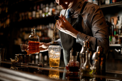 调酒师使用烧杯小心地将酒倒入玻璃杯中
