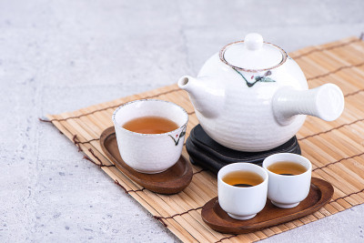 热茶在白色茶壶和杯子上筛过亮灰色水泥背景，特写，复制空间设计理念。