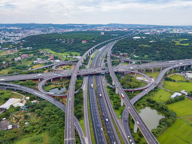 在高速公路路口行驶的汽车鸟瞰图。桥梁道路与绿色花园和树木联系在一起的建筑理念。前视图。城市城市，台北