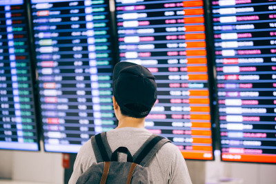年轻男性旅客在登机时间监视器屏幕上观看和等待航班时间