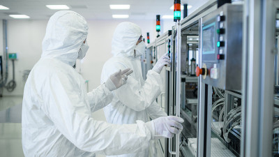 一组科学家穿着无菌防护服在现代工业3D打印机器上工作。制药、生物技术和半导体制造工艺。