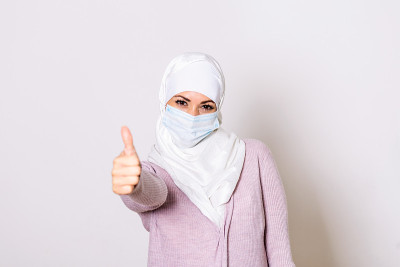 穆斯林妇女戴着保护面罩，翘起大拇指。妇女戴着面纱，保护人类肺部的冠状病毒。MERS-CoV、SARS